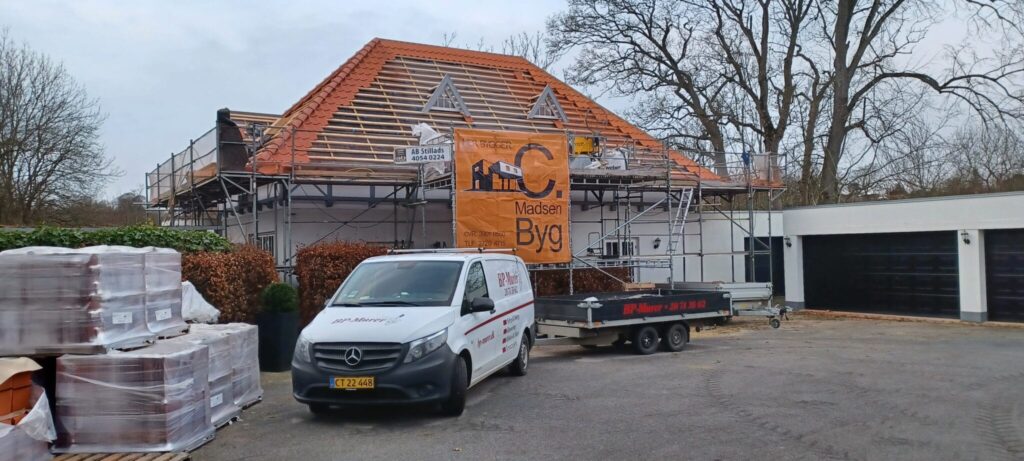 Tagrenovering af hus med byggematerialer og stillads