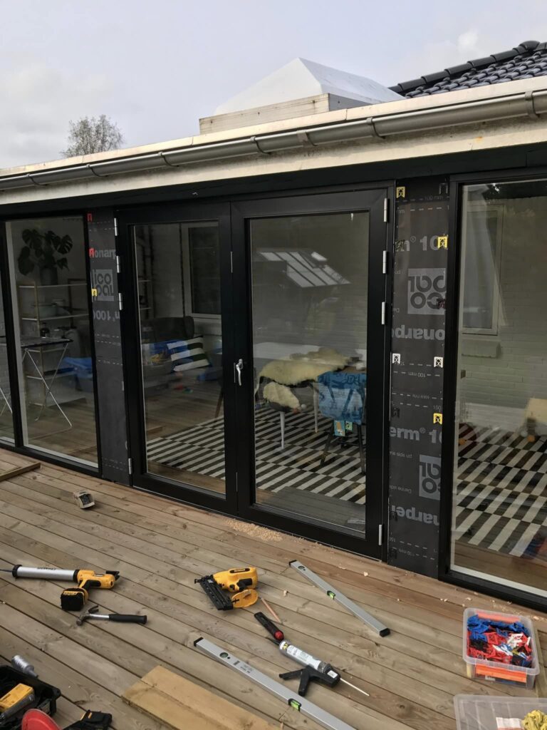 Renovering af terrasse med sorte glasdøre og værktøj
