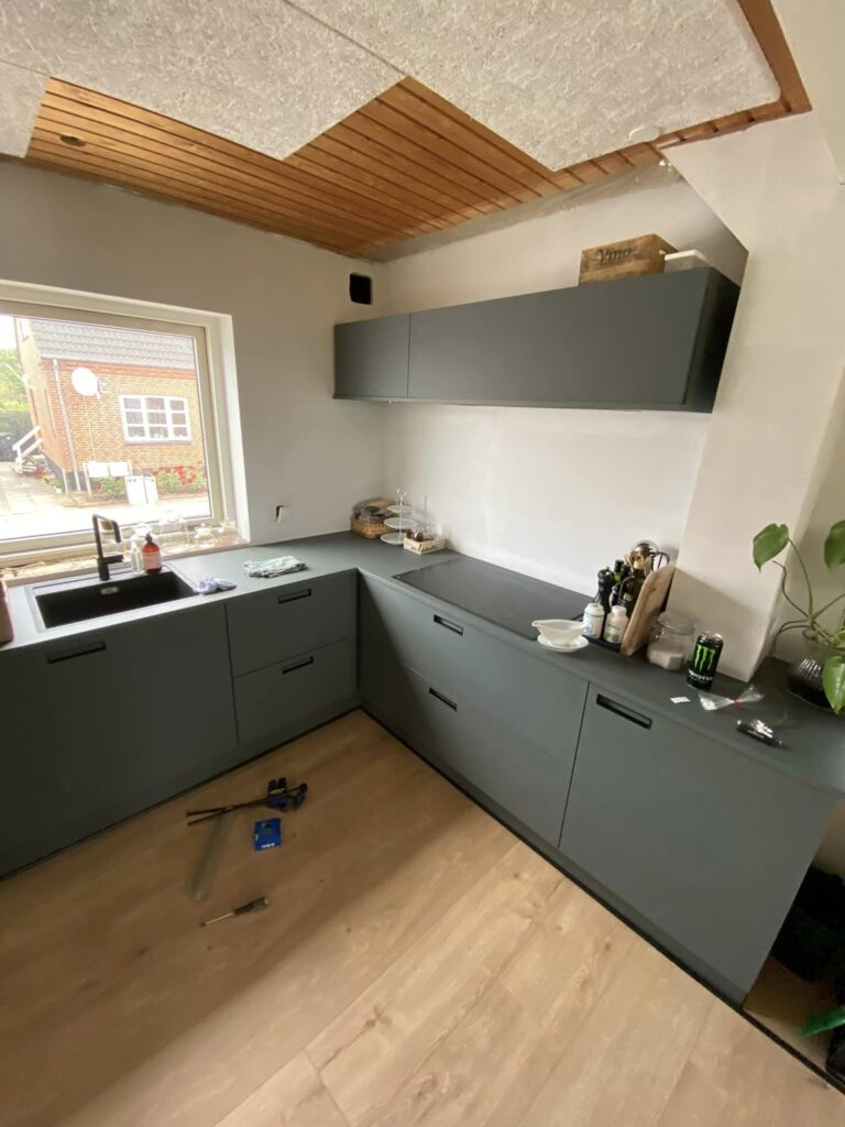 Moderne køkken med grønne skabe og trægulv