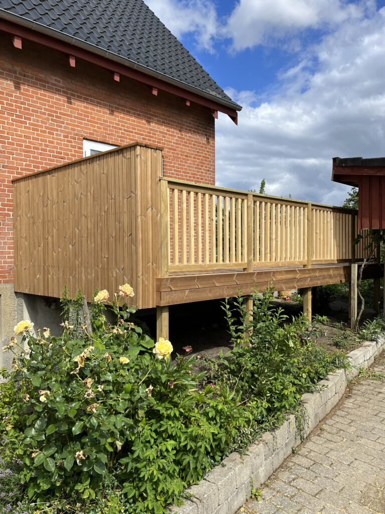 Nybygget træterrasse ved murstenshus med have